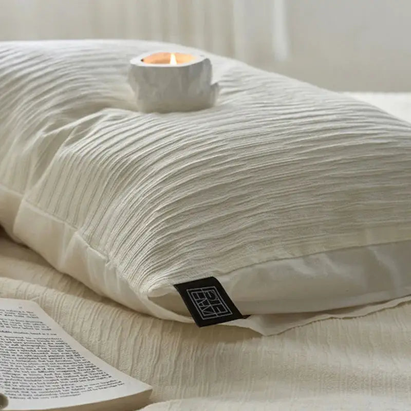 Cream textured cotton foam yarn bedding set pillow with soft off-white crinkled fabric and black brand tag