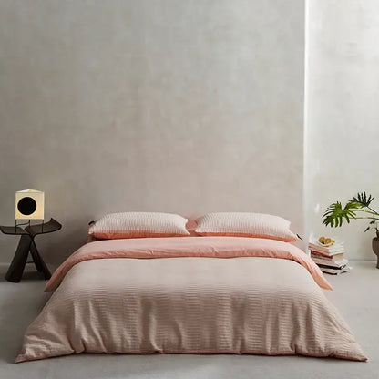 A soft peach ribbed duvet bedding set made of cotton foam yarn with matching pillows in a minimalist bedroom design