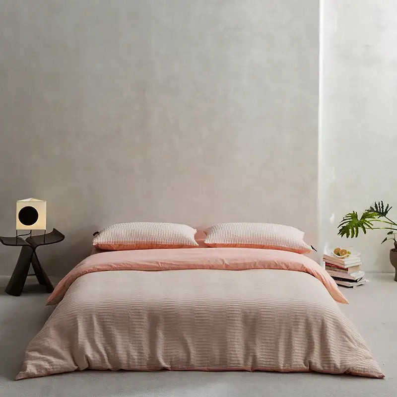 A soft peach ribbed duvet bedding set made of cotton foam yarn with matching pillows in a minimalist bedroom design