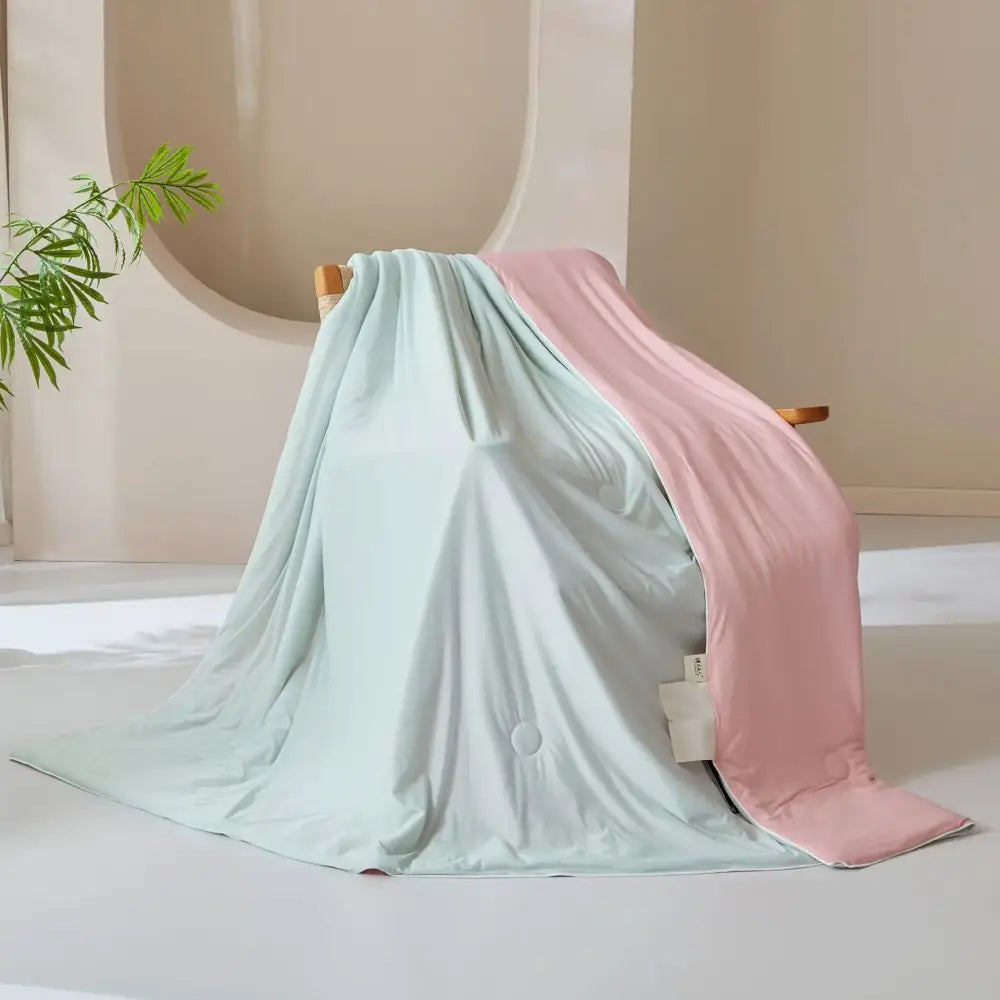A two-toned pastel mint and blush pink ice cream silk cream silk quilt draped over a wooden chair by decorbites ice cream