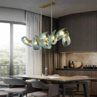 A modern pendant light with translucent teal decorbites blue glass shades and gold-toned metal accents for luxury decor