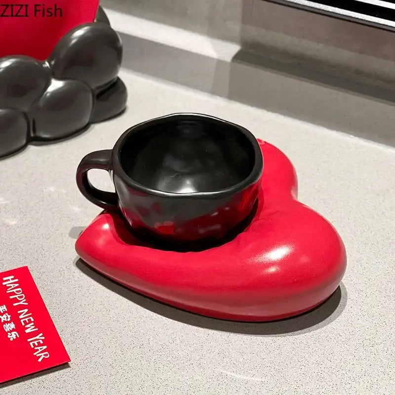 A glossy black ceramic mug with matching handle on a vibrant red heart porcelain coffee saucer from decorbites creative heart set