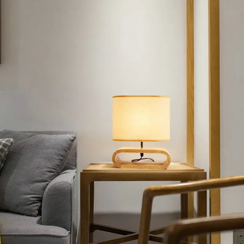 A warm-toned beige linen creative nordic wooden table lamp with a minimalist curved wooden base for bedroom decorbites creative nordic