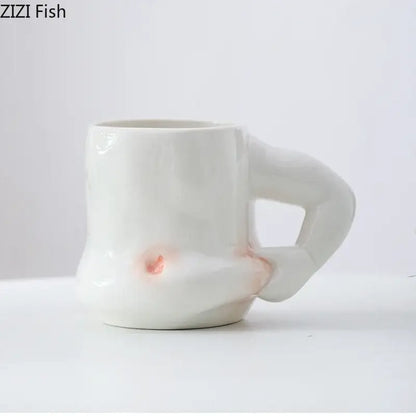 White ceramic creative pinch belly cup with sculpted hand handle and subtle pinkish orange glaze accents for dining room use
