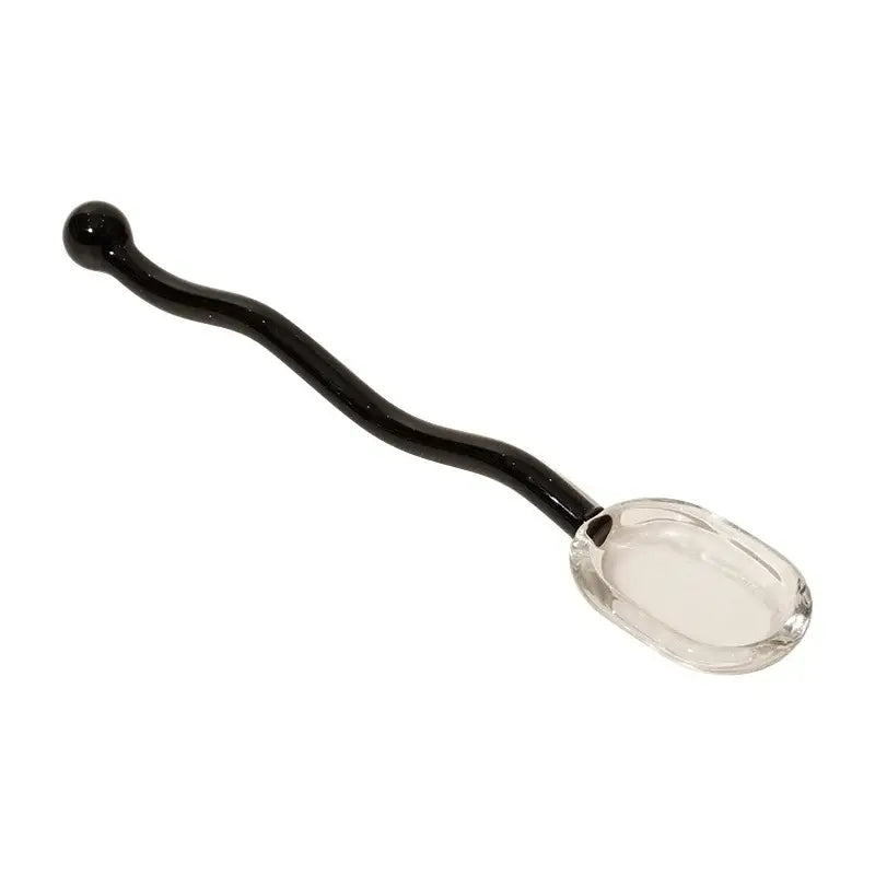 A sleek black glass spoon with a clear faceted bowl and curved handle for creative coffee and glass spoon dessert use