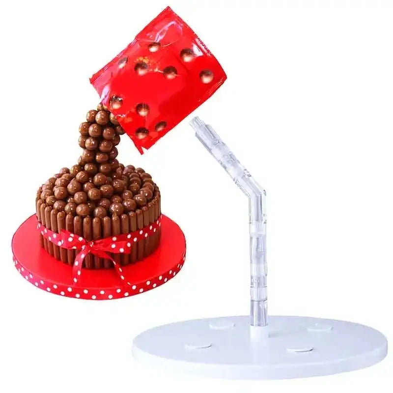 Red plastic cup pouring chocolate malt balls onto kitkat cake on creative red and white cake stand support for baking
