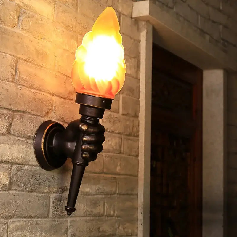 A creative torch hand wall lamp in dark bronze with a warm glowing flame-shaped glass for living room decorbites creative torch