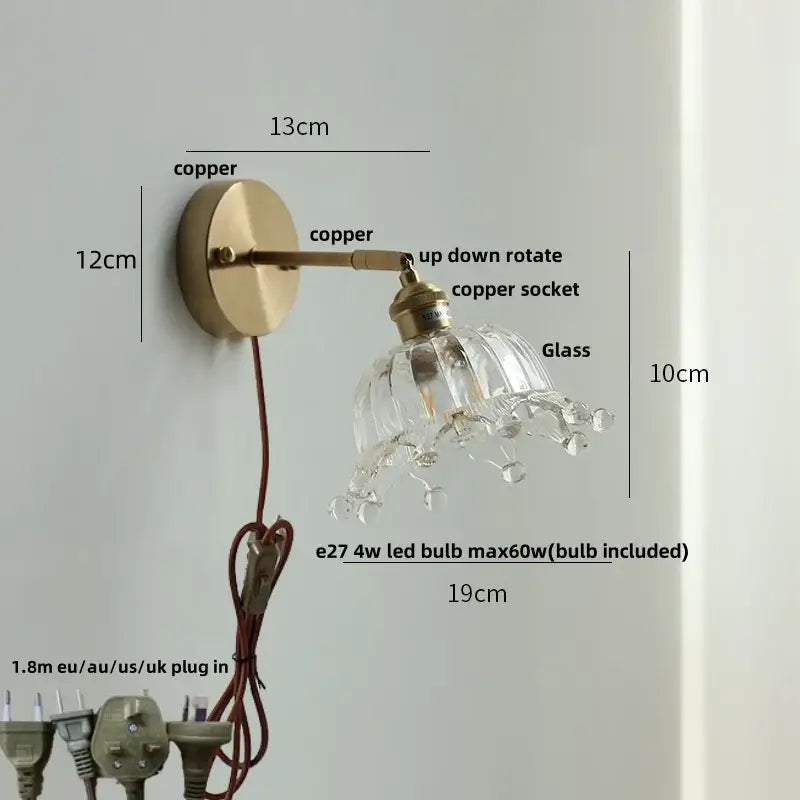 A delicate brass decorbites crown glass led wall sconce with clear faceted glass shade and crystal droplets for bedroom use