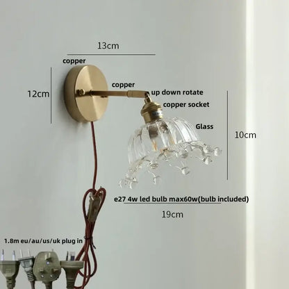 A delicate brass decorbites crown glass led wall sconce with clear faceted glass shade and crystal droplets for bedroom use