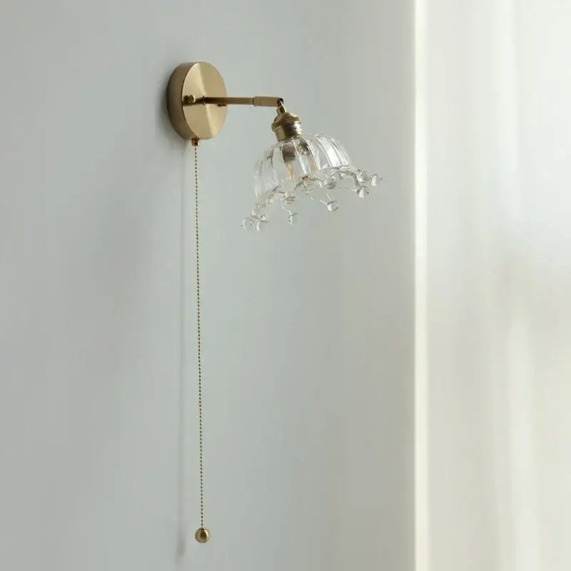 A brass decorbites crown glass led wall light with clear faceted glass shade and dangling crystal droplets for bedroom decor
