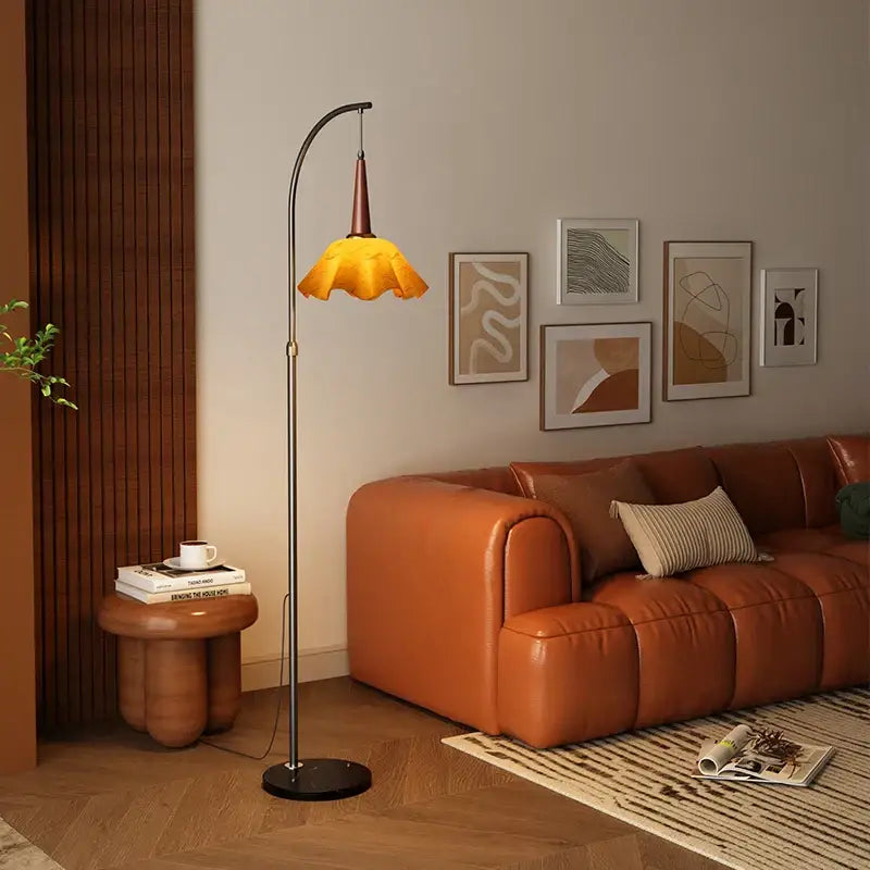 Curved black floor lamp with polished metal frame and amber fabric shade beside a living room shelf for living room floor use