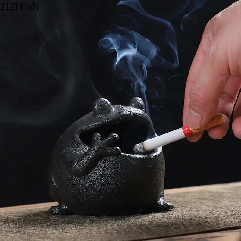 Black ceramic ashtray shaped like a cute big belly frog with textured surface and open mouth design for living room decor