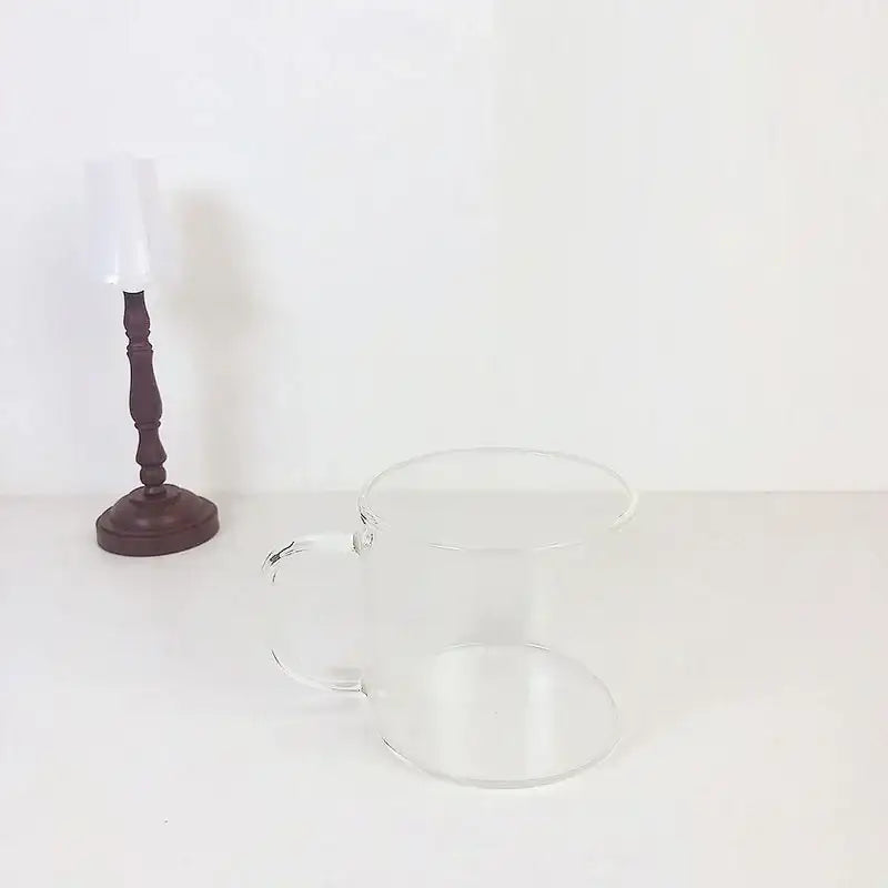 Clear glass mug with smooth handle featuring a cute cartoon cow pattern and spoon lid for dining room use