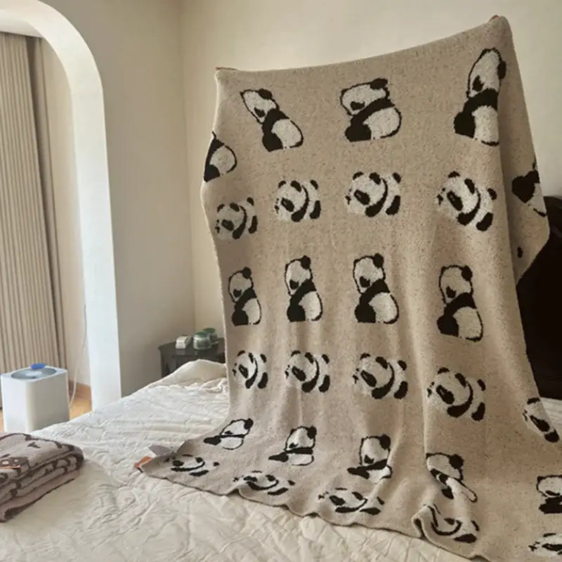 Beige knit blanket with a repeating pattern of black and white pandas for a cute cartoon half flannel bedroom throw