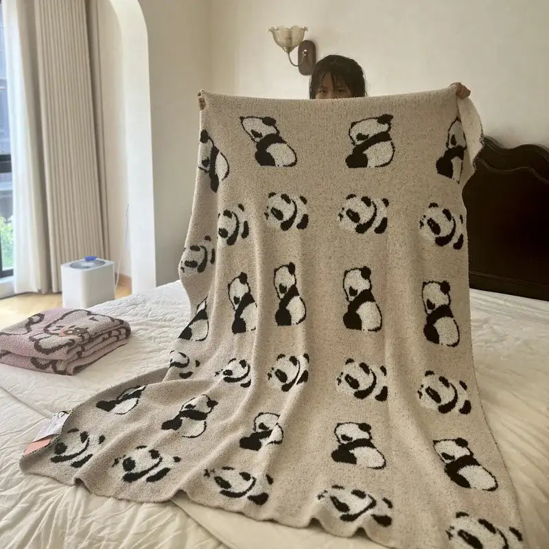 Beige knitted blanket with a cute cartoon black and white panda pattern in a pink and beige cartoon half flannel throw