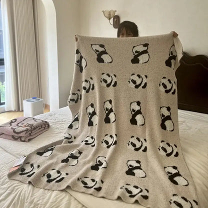 Beige knitted blanket with a cute cartoon black and white panda pattern in a pink and beige cartoon half flannel throw