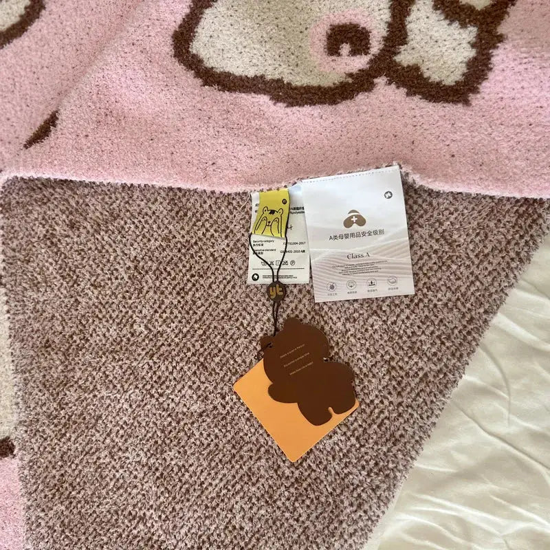 A cute cartoon pink and beige cat flannel blanket with a soft knitted plush bear pattern for bedroom throw use