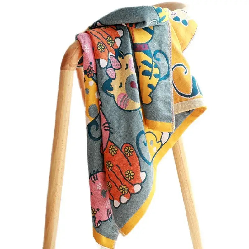 A cute cat bath towel with a gray base and colorful playful animal prints in pink yellow and orange hues ideal for bath use