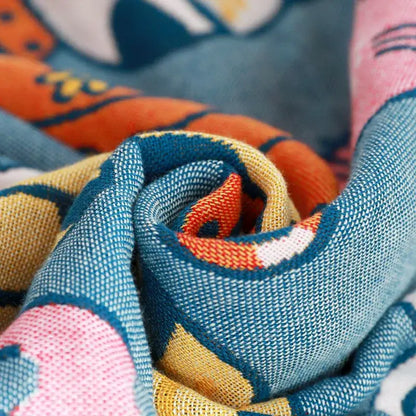 A cozy blue knitted cat bath towel with a playful orange and yellow animal pattern for bathroom wrap use