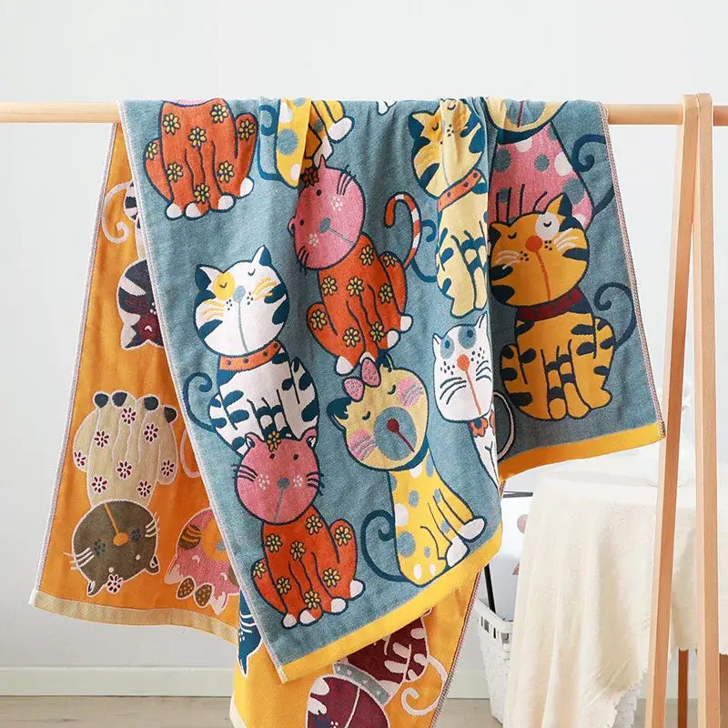 A soft blue knitted cute cat bath towel featuring colorful cartoon cats in various outfits and poses for bathroom use