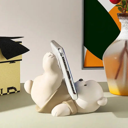 Cream ceramic bear cellphone stand holding a silver smartphone for bedroom desktop decoration
