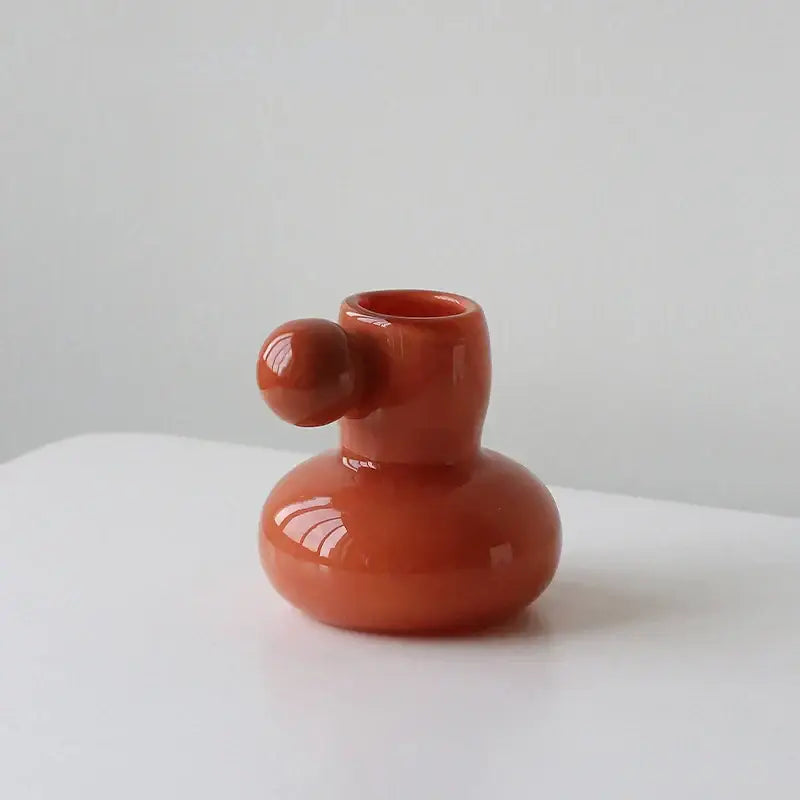 A glossy terracotta ceramic candle holder with a rounded base and small spherical knob for decorbites cute glass ball decor