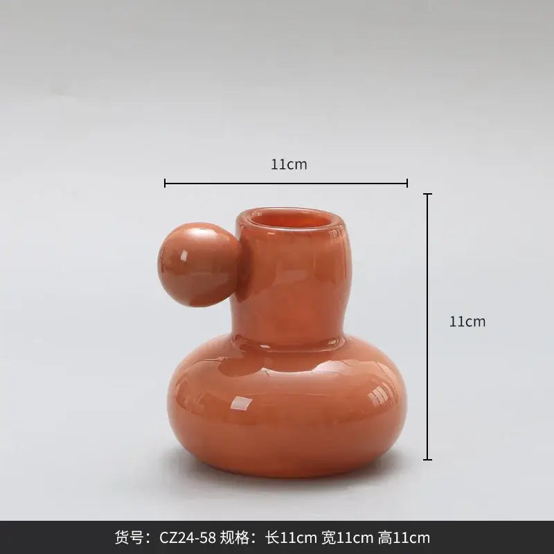 A glossy terracotta ceramic candle holder with a rounded base and spherical handle for decorbites cute glass ball decor
