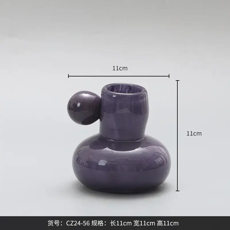 A glossy purple ceramic candle holder with a rounded body and cute glass ball decor bites design for living room decor