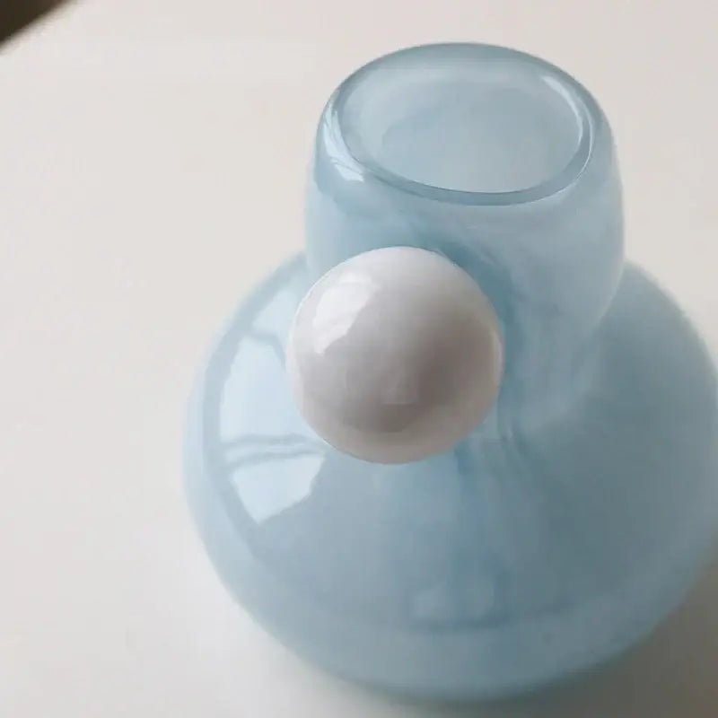 A translucent light blue glass candle holder with a glossy white spherical accent for decorbites cute glass decor