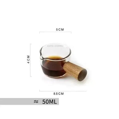 A clear glass cup with wooden handle holding dark liquid featuring a pink bow tie for kitchen coffee use
