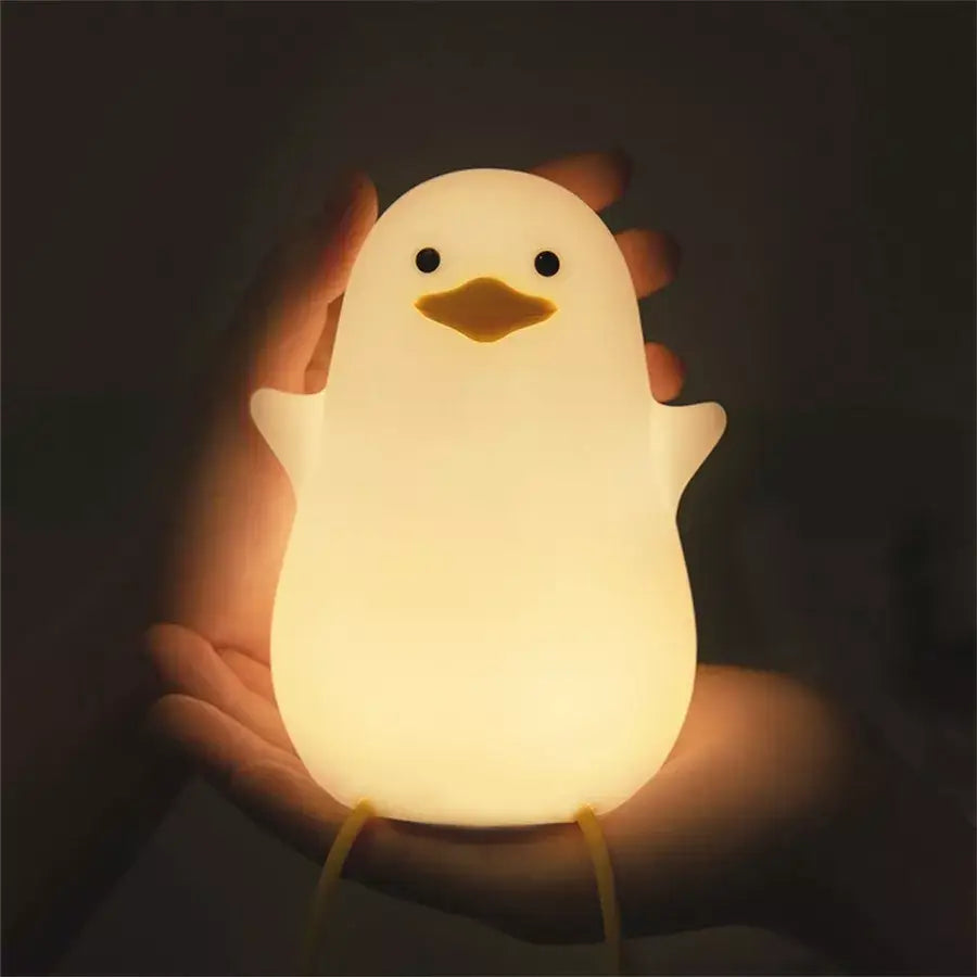 A soft glowing white silicone penguin night light with black eyes and yellow beak usb rechargeable night lamp
