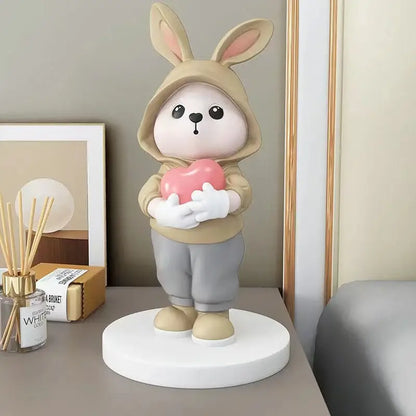 Cute beige bunny desk figurine wearing a hooded outfit and holding a pink heart for home decor