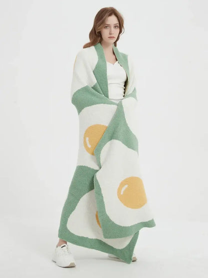 A cozy green knitted throw with a cute poached egg pattern featuring white and yellow accents for bedroom decorbites decor