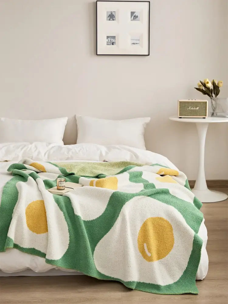 Cozy cream and green knitted throw blanket with playful oversized yellow yolk pattern perfect for decorbites cute poached decor