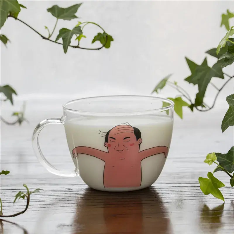 Clear glass coffee mug featuring a cartoon pink balding man with arms outstretched heat resistant for kitchen use
