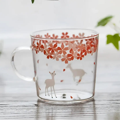 Clear glass coffee mug with pink cherry blossom pattern and beige deer silhouettes, heat resistant for kitchen use