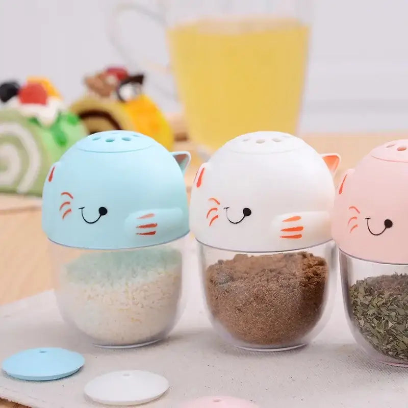 Three pastel-colored cat spice jars with clear glass bodies and plastic lids in a decorbites cat spice jar set