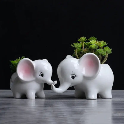 Cute white ceramic elephant succulent planter with pink ear accents and black eyelashes holding green succulents