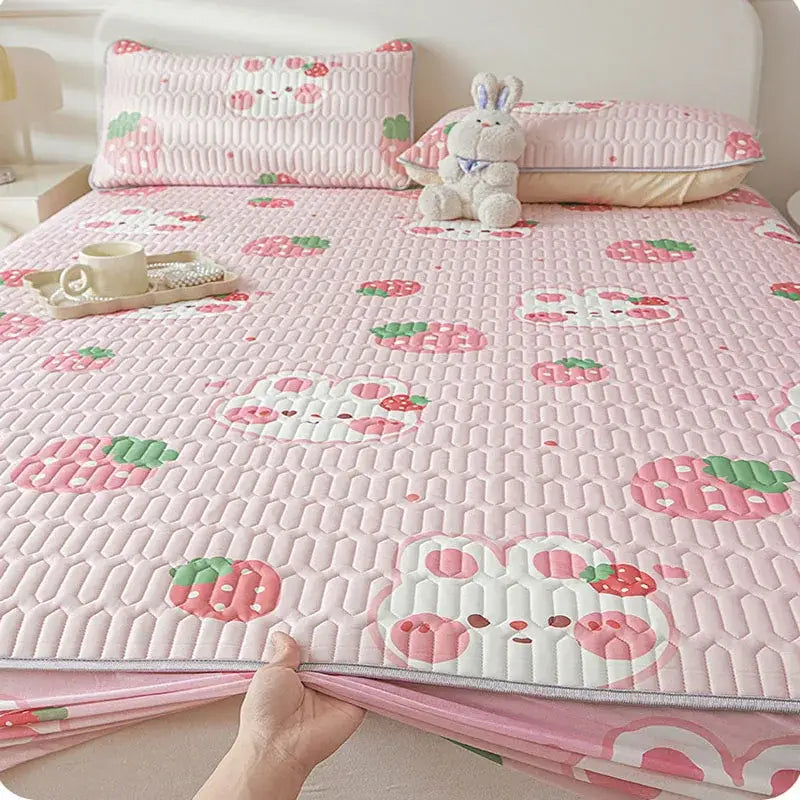 Pink quilted bed pad fitted sheet with cute cartoon pattern featuring strawberries and white embroidered bunny faces