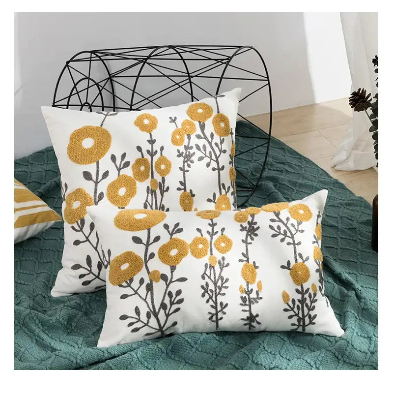 White throw pillows with embroidered yellow and gray daisy floral geometric embroidery for living room decor by decorbites