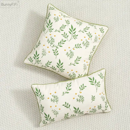 Cream-colored cushion cover with green leaves and yellow dot embroidery bordered in olive green decorbites daisy floral
