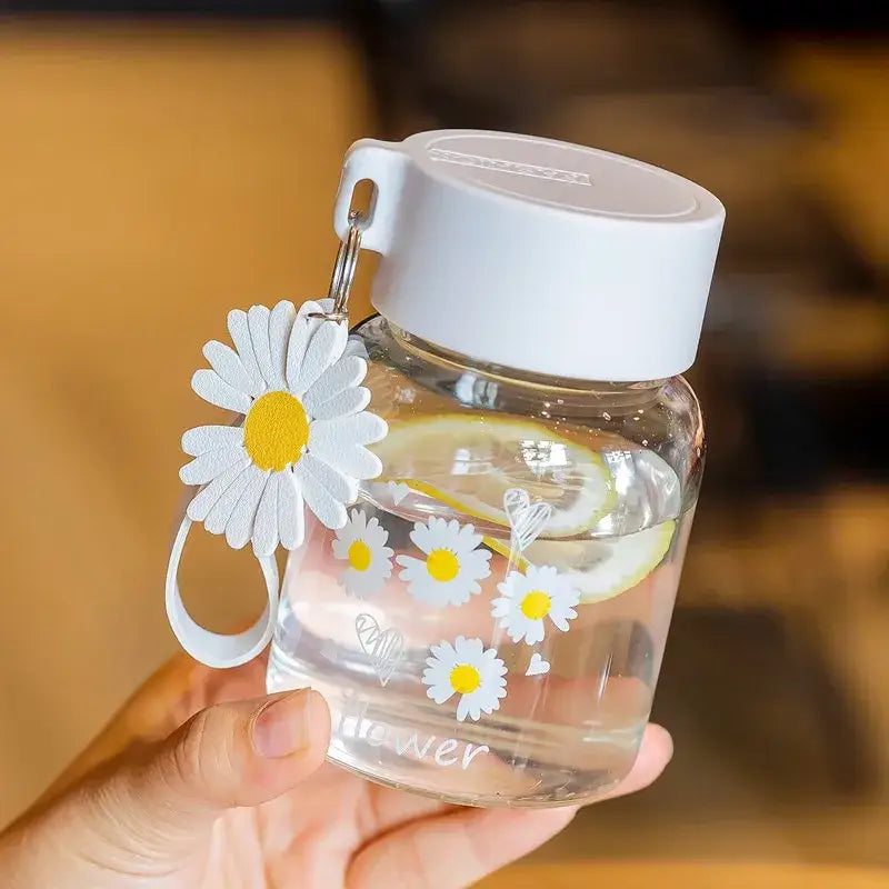 Clear glass daisy flower glass water bottle with white and yellow decals, white lid, and decorbites daisy flower charm