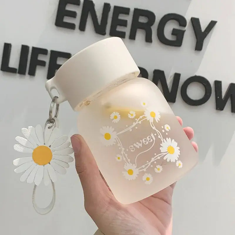 A frosted white daisy flower glass water bottle with yellow flower decals sweet script and a dangling decorbites daisy flower charm