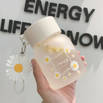 A frosted white daisy flower glass water bottle with yellow flower decals sweet script and a dangling decorbites daisy flower charm