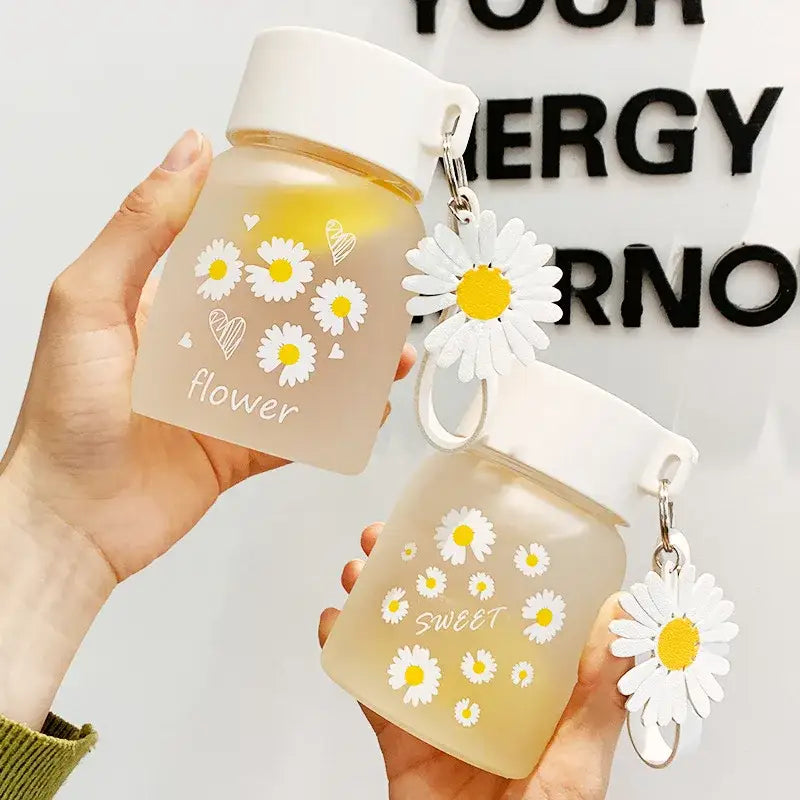A translucent peach daisy flower glass water bottle with white lid and decorbites daisy flower keychain charm