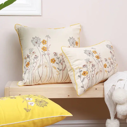 Cream-colored pillow cover with yellow and gray dandelion floral embroidery and matching yellow piping trim decorbites dandelion floral