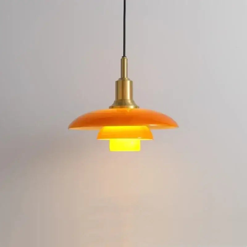 Orange layered glass pendant light with brass hardware serves as a focal point in dining room lighting fixture