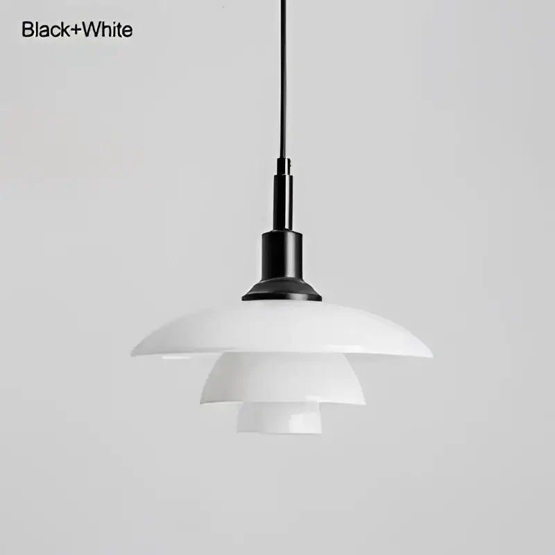 Danish tiered frosted glass pendant light with black and white brass fixture serving as a modern dining room focal point