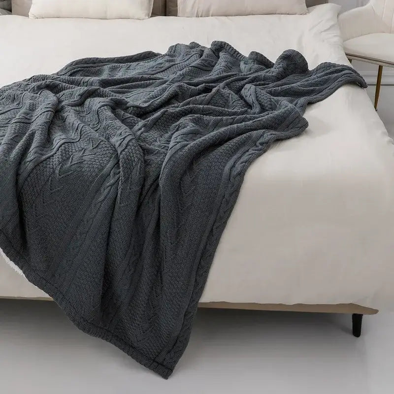 A cozy double layer dark gray fishbone knit blanket with white fleece lining draped over a bed for decorbites cozy double use