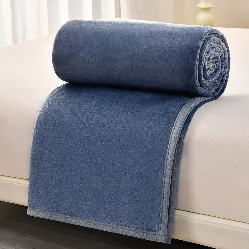 A plush navy blue fleece blanket rolled on a light surface alongside dark gray and light gray decorbites cozy flannel blanket